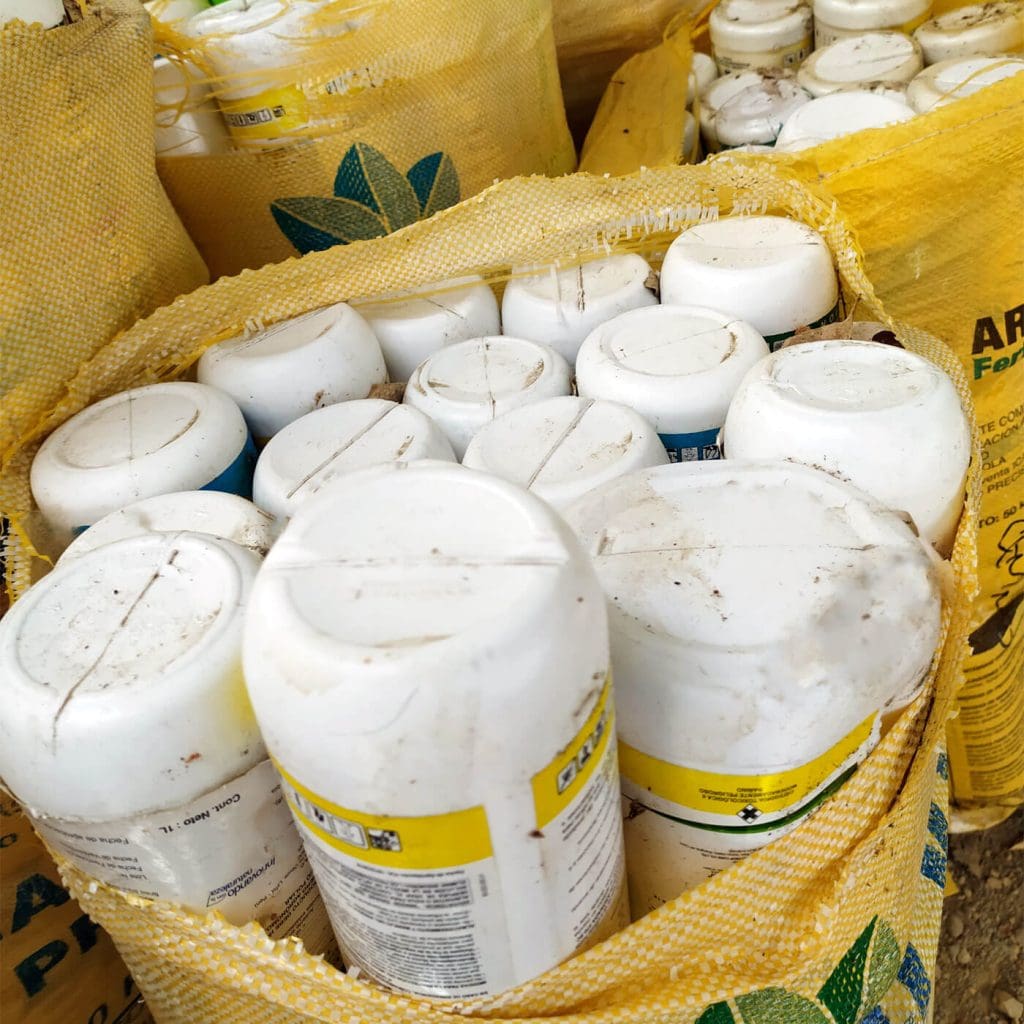 Un montón de botellas blancas y amarillas sobre un montón de tierra, esperando el certificado de devolución.